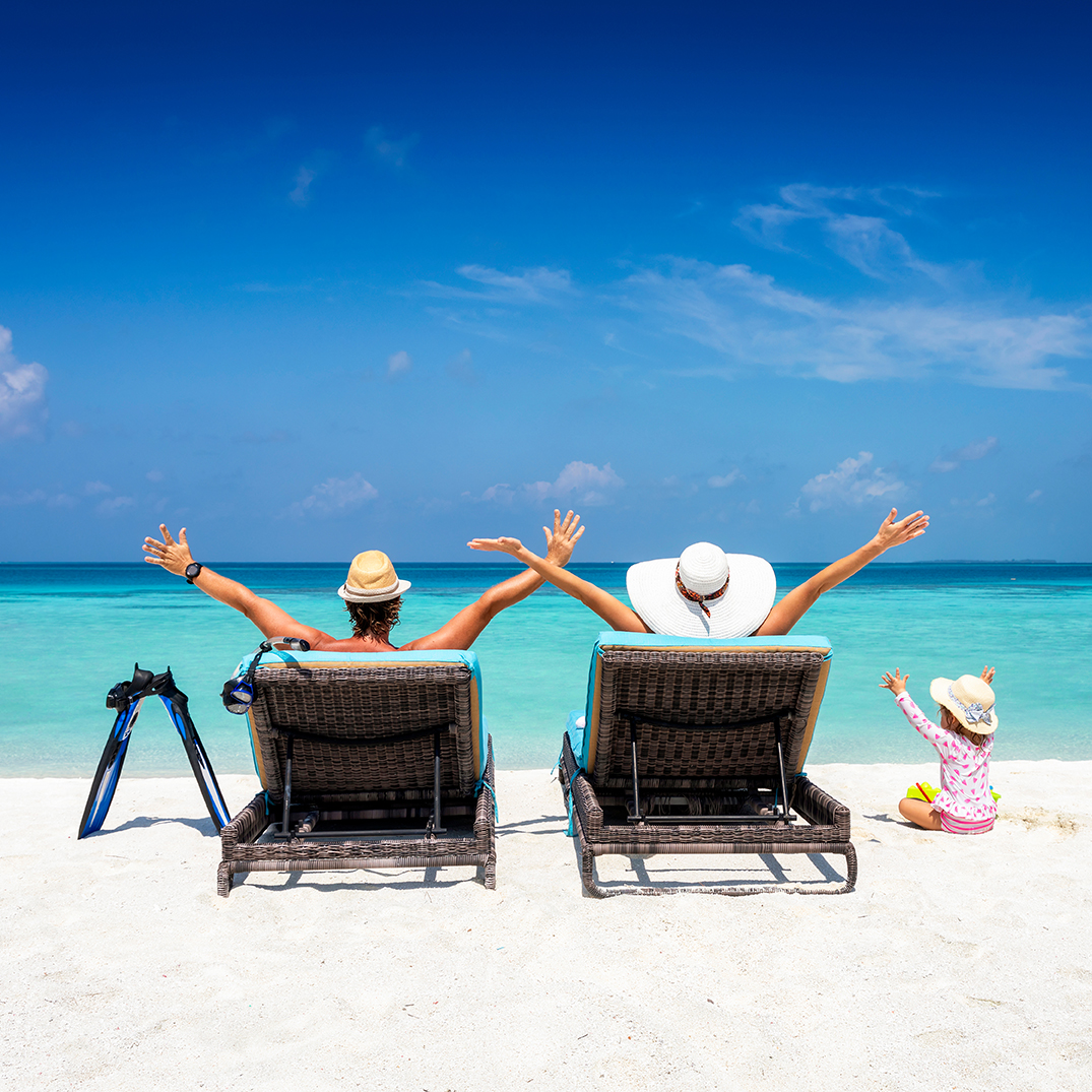 Happy family on sunbeds enjoys their vacation on a tropical beac