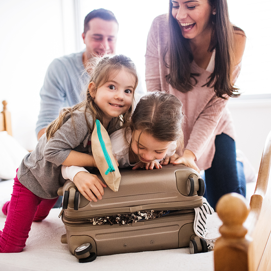 Portrait of a young happy family with two children packing for holiday at home.